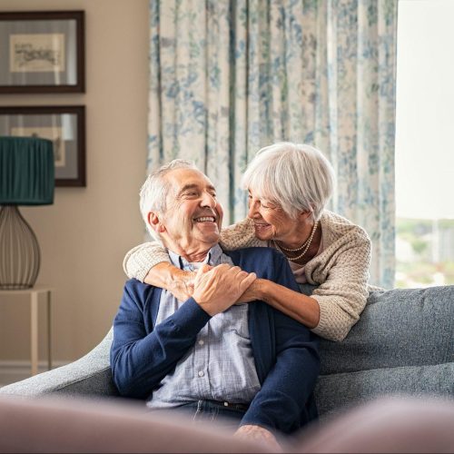 A smiling senior couple sit in their classic and modern home.